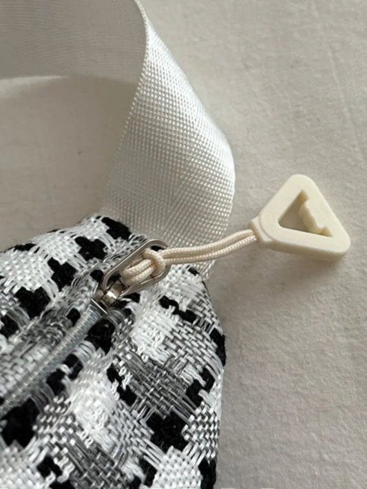 Crossbody-/Umhängetasche mit breitem kariertem Schulterriemen.